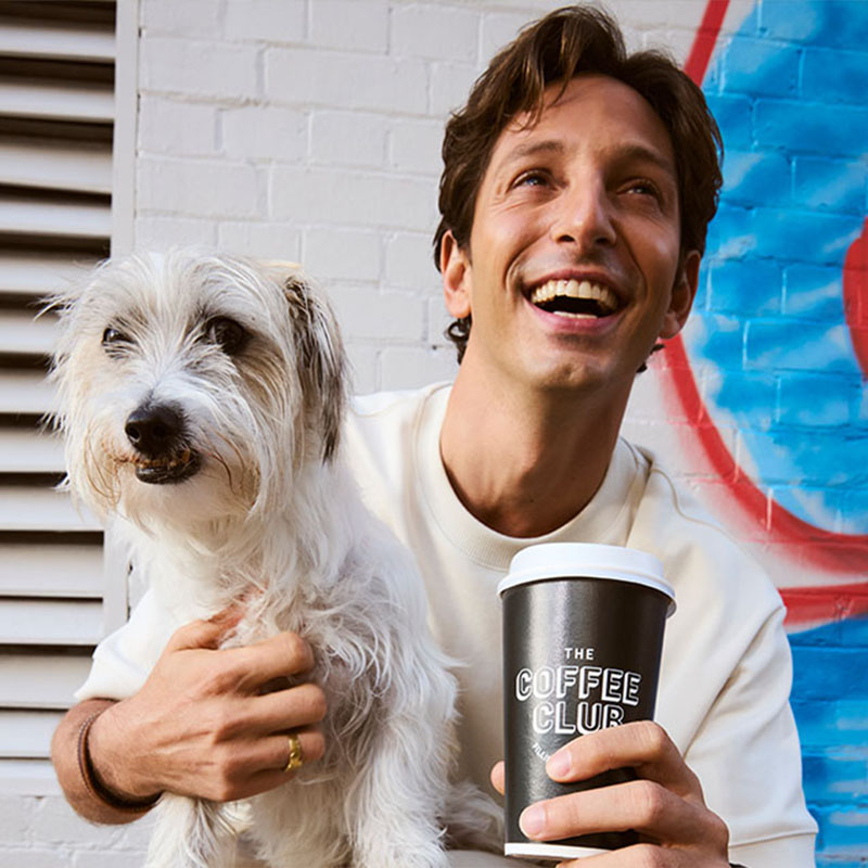 person holding coffee with dog